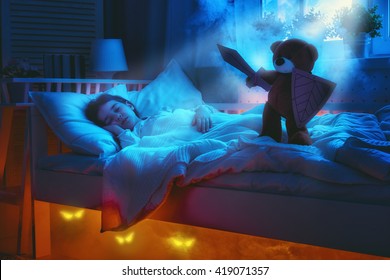 Nightmare For Children. Little Child Girl Is Afraid Of Monsters In The Dark Of Night. Frightened Little Girl And Her Teddy Bear Friend Are Protected Against Monsters.