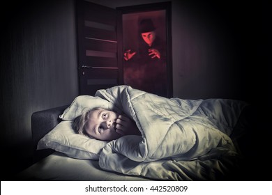 Nightmare. Scared Boy Lying In The Bed While The Masked Stranger Standing In A Doorway