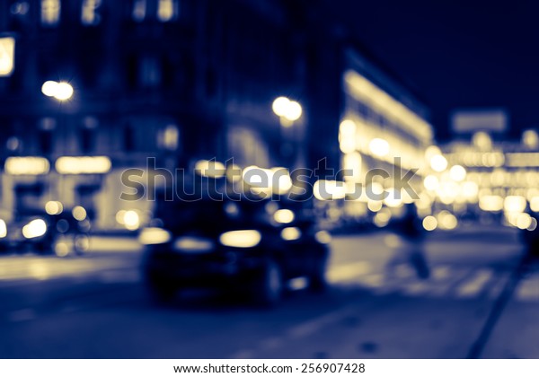 Nights lights of the big\
city, cars at night with pedestrian on the avenue. Image in blue\
toning