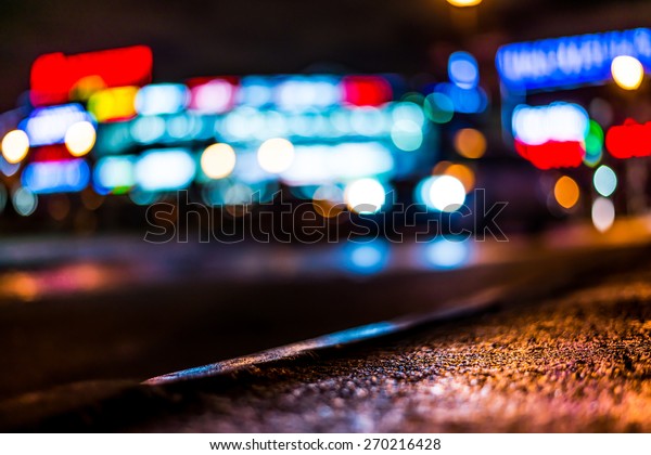 Nights lights of the big city, glowing shop\
windows and cars on the\
avenue