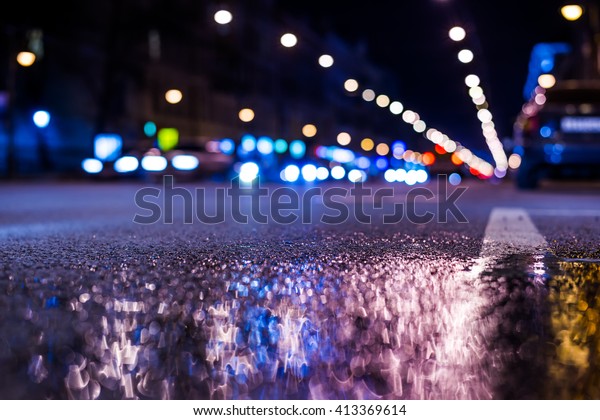 Nights lights of the big city, the main city street\
in rushhour. Close up view from the level of the dividing line, in\
blue tones
