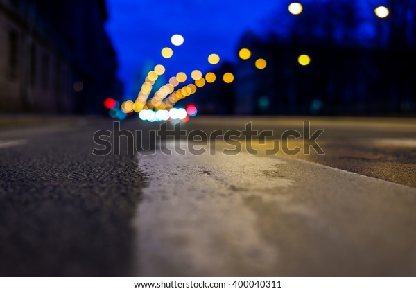 Nights lights of the big city, the night avenue\
with headlights of the approaching cars. Close up view of a\
pedestrian crossing\
level