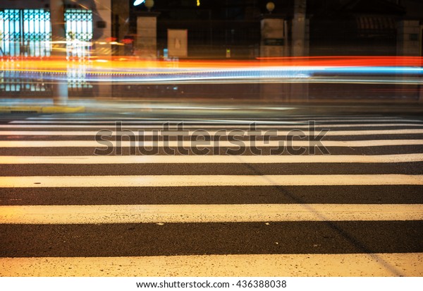 Nights lights of the big city, the night avenue\
with road markings and headlights of the approaching cars, close up\
view from asphalt level