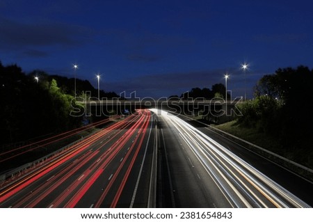 A nightscape featuring bright light trails over a motorway.