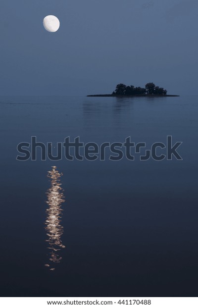 Nightscape of river\
with moon over small\
island.