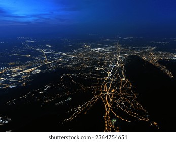 A nighttime aerial view of Brașov city in Romania reveals a beautiful perspective, with the web of street lights forming a pattern of interconnected luminous pathways.  - Powered by Shutterstock