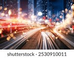 Nighttime cityscape with tall buildings, streetlights, and blurred streaks of light from moving vehicles.