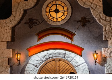 Nighttime image of a decorated clock tower during. Christmas Large wooden door with metal accents and coat of arms Dramatic archway in vibrant orange and red Elegant illuminated clock face with Rom.