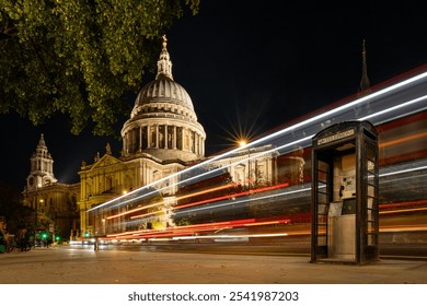 Nighttime long exposure of St. Paul's Cathedral in London with light trails from passing buses and a vintage telephone booth in the foreground - Powered by Shutterstock