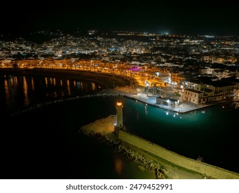 A nighttime marina scene with shimmering lights of the town reflecting in the water - Powered by Shutterstock