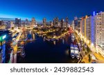 Nighttime panorama of Rotterdam “Leuvehaven“ harbour at blue hour on river Maas in the Netherlands. Reflections of modern buildings and colorful lights and illumination. Boats and vessels moored.