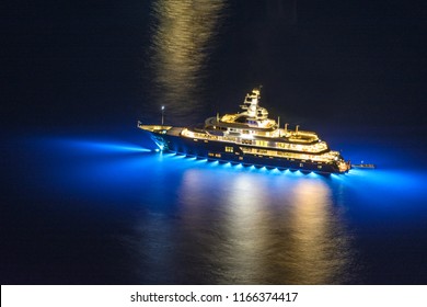 Nighttime photo of a lit yacht with blue reflectors on the underside to draw in the fish