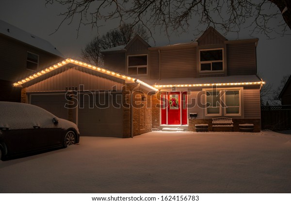 Nighttime Shot of a Detached Suburban\
House With a Red Door All Lit Up with Christmas\
Lights