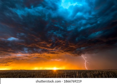 A nighttime, tornadic mezocyclone lightning storm shoots bolt of electricity to the ground and lights up the field and dirt road in Tornado Alley. - Shutterstock ID 1866769219