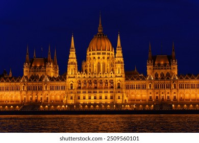 Nighttime view of Hungarian Parliament Building with river in foreground. - Powered by Shutterstock