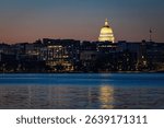 Nighttime view of the illuminated Madison Wisconsin skyline with the glowing State Capitol reflected in Lake Mendota