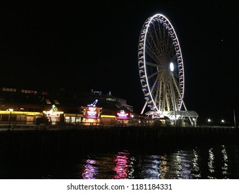 A nighttime view of the pier, river, and ferris wheel in Seattle, Washington - Powered by Shutterstock