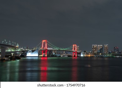 Nightview of Rainbow Bridge illuminated in red as a sign of Tokyo Alert, coronavirus alert for Tokyo area, in Odaiba Japan.