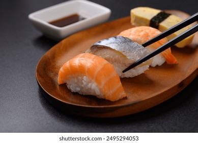 Nigiri sushi salmon, mackerel, shrimp and sweet egg (tamago) on wooden plate eating by chopsticks, Japanese food - Powered by Shutterstock