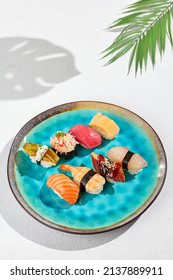 Nigiri sushi set on ceramic plate in minimal style. Nigiri sushi assorted with fish, crab, eel, tuna, shrimp, salmon and avocado. Simple sushi set on white background with hard shadows