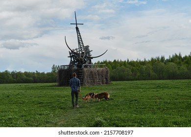 Nikola-Lenivets, KALUGA REGION, Russia - 15 May, 2022. Ugra National Park, Park Of Modern Art Objects In Nature. Man Is Traveling With Two Dogs, View From Back. Sculpture Wooden Gilded Taurus.