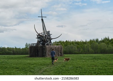 Nikola-Lenivets, KALUGA REGION, Russia - 15 May, 2022. Ugra National Park, Park Of Modern Art Objects In Nature. Man Is Traveling With Two Dogs, View From Back. Sculpture Wooden Gilded Taurus.