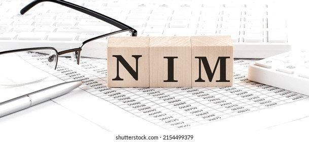 NIM written on wooden cube with keyboard , calculator, chart,glasses.Business - Shutterstock ID 2154499379