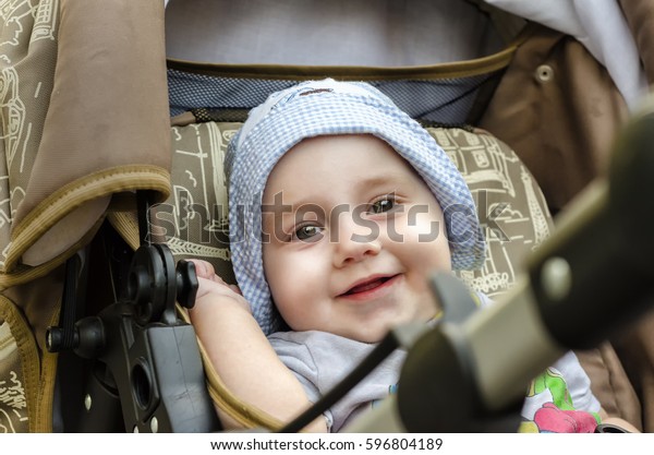Nine month old baby boy sitting in the stroller on\
beautiful summer day