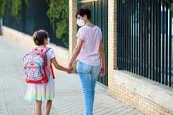 Nine years old girl with bag walking with her mother hand in hand wearing masks. Back to school concept., a Person Photo by javi_indy