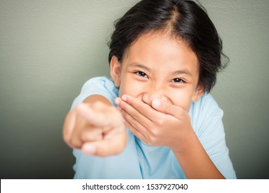 Nine Years Old Girl Close Her Mouth With A Hand To Cover Laughing And Points Up To The Camera Like Some Adult Make Something Funny