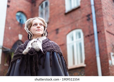 Nineteenth-century woman, elegantly dressed, walks through the courtyard of a castle