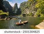 Ninh Binh, Vietnam: View of the stunning Trang An river and famous karstic landscape with an ancient padoga in nothern Vietnam on a sunny day.