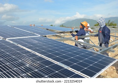Ninh Thuan, Vietnam - May 18 2020: Workers and engineers in uniform and hardhats working and installing photovoltaic panels on a metal basis on a solar farm - Construction site and industrial concept - Shutterstock ID 2213254019