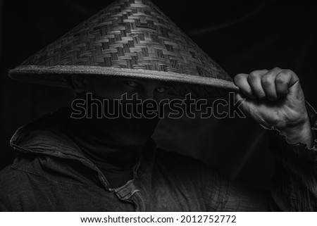 Ninja in hat posing over dark background