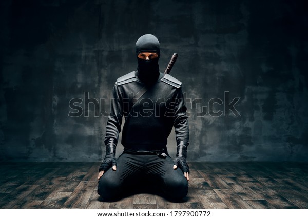 Ninja kneeling posing with a sword over\
black background. japanese fighter\
concept
