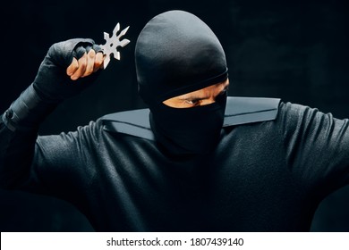 Ninja with a sword and shuriken ready to stab enemy over black background. japanese fighter concept