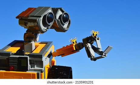 NITRA, SK - MARCH 12, 2021: LEGO robot model of Wall-E from Disney Pixar movie watching two LEGO Minecraft bees sitting on his arm, spring blue skies in background, morning sunshine.