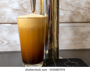 Nitro Cold Brew Coffee In A Clear Glass With Fine Nitrogen Bubbles And A Smooth Texture On A Keg Coffee Dispenser.