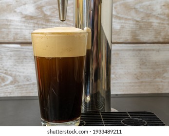 Nitro Cold Brew Coffee In A Clear Glass With Fine Nitrogen Bubbles And A Smooth Texture On A Keg Coffee Dispenser.