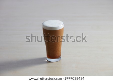 Nitro cold Brew coffee glass on wooden table. Closeup of cold Nitro coffee beer trendy drink with frothy foam isolated on white background