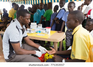 Nkokonjeru, Uganda. June 22 2017. A Young Man Testing A Boy For HIV By Pricking His Finger And Drawing Blood.