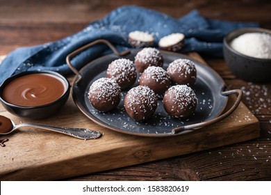 No bake delicious candy, sweet coconut balls dipped in chocolate on rustic wooden background