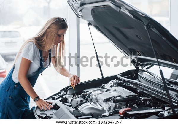 No breaks, all\
must be perfectly done. On the lovely job. Car addicted woman\
repairs black automobile\
indoors.