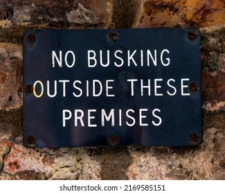 No Busking Outside These Premises sign on the exterior of a shop.