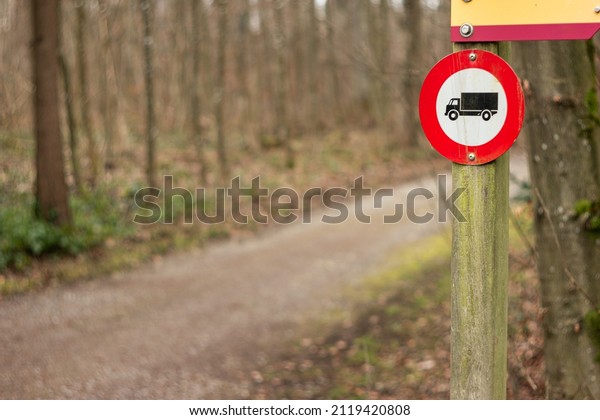 No cars and trucks allowed\
stop sign on a wooden post in the forest near rural road, no\
people.
