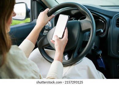 No Cell Phone Use While Car Driving. Woman Driver Holding Mobile Phone A Steering Wheel In A New Car. Selective Focus, Cropped.