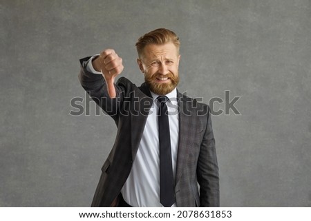 No, I don't like bad business ideas. Male office worker entrepreneur looks at you doing thumb down dislike sign with embarrassed displeased cringed face expression grimace isolated on grey background