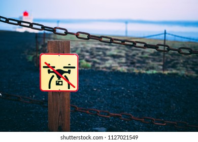 No drone flight sign on the fence with the ground grass and sky light house on the background in Iceland