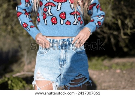 No face e-commerce fashion: Close up photography of urban outfit. Blue sweater with red mushrooms stamps and jean short