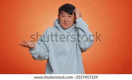 No idea, I dont know answer. Puzzled clueless uncertain asian handsome man raising hands in helpless gesture, embarrassed confused by difficult question. Confused one guy on orange studio background